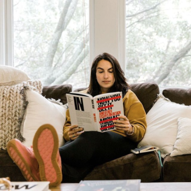Photo of Focus Lab team member, Genina, reading a book on a couch.