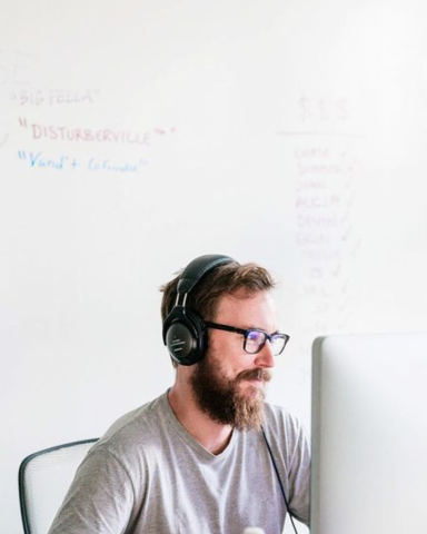Photo of Focus Lab team member, Chase, smirking while working at his desk with headphones on.